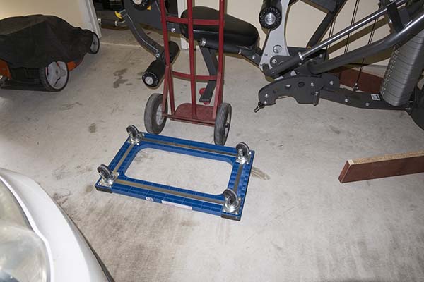 Photograph of Hoist V5 home gym, showing hand truck and reversed dolly as wheel block used to remove an assembly process under frame block.